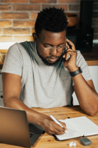 adult male uses cell phone while taking notes in journal