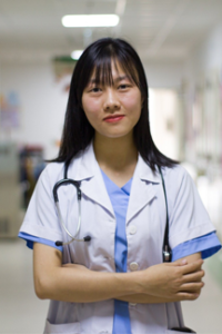 nurse in blue scrubs with stethoscope stands with arms crossed