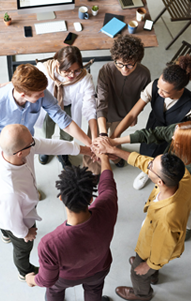 group of people stand in circle with hands clasped together in middle