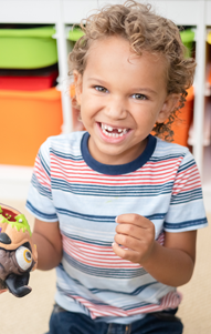 child in striped shirt holds toy in classroom